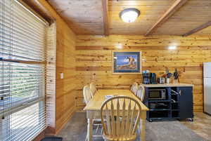 Dining room featuring wood ceiling with exposed beams and wooden walls