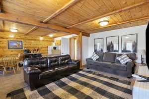 Carpeted living room with wooden ceiling with exposed beams and wood walls