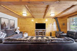 Living room with wooden ceiling, a wood stove, and wood walls
