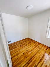 Empty room featuring hardwood / wood-style floors, baseboards, and crown molding