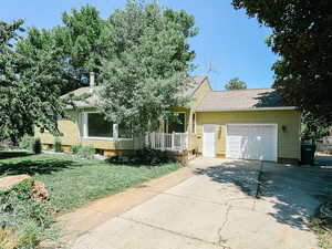 Obstructed view of property featuring concrete driveway, a garage, a front yard, and a shingled roof