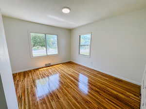 Unfurnished room with healthy amount of natural light, wood finished floors, and baseboards