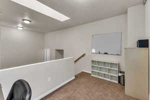 Unfurnished office with carpet floors, a skylight, and baseboards