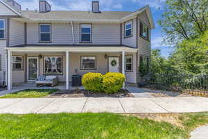 Townhome / multi-family property with a chimney, a porch, and a shingled roof