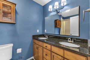 Full bathroom featuring double vanity, toilet, and curtained shower