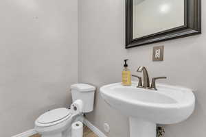 Bathroom with toilet, a sink, baseboards, and tile patterned floors