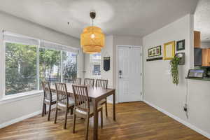 Dining area featuring wood finished floors, baseboards, and a textured ceiling