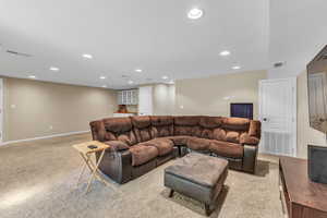 Living area with light colored carpet, recessed lighting, and baseboards