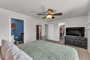 Bedroom with a walk in closet, carpet flooring, a closet, baseboards, and ensuite bathroom