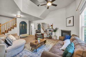 Living area with stairway, a ceiling fan, a glass covered fireplace, and carpet