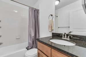 Full bathroom featuring vanity, shower / tub combo with curtain, and toilet