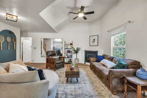 Carpeted living area with a glass covered fireplace, ceiling fan, and baseboards