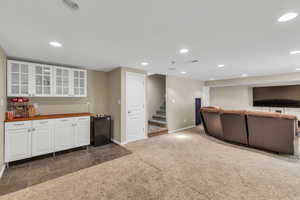 Kitchen featuring white cabinetry, recessed lighting, dark colored carpet, glass insert cabinets, and butcher block countertops