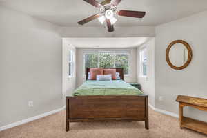 Bedroom with light colored carpet, baseboards, and a ceiling fan