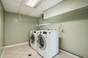 Washroom with light tile patterned floors, independent washer and dryer, and baseboards