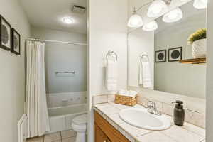 Bathroom featuring vanity, light tile patterned flooring, a textured ceiling, and shower / bath combo with shower curtain