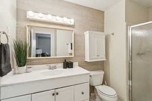 Bathroom featuring a shower stall, vanity, and tile walls