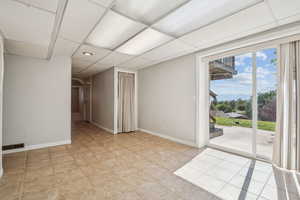 Empty room with baseboards, a paneled ceiling, and wooden walls