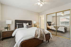 Carpeted bedroom featuring ceiling fan and a closet