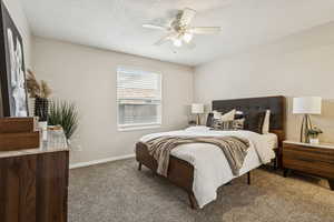 Carpeted bedroom with a ceiling fan and a textured ceiling