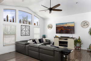 Living area with a ceiling fan, dark wood-type flooring, healthy amount of natural light, and high vaulted ceiling