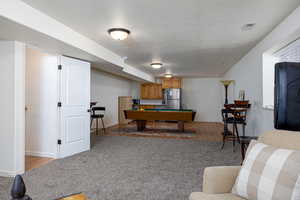 Game room featuring billiards, light wood finished floors, baseboards, and a textured ceiling