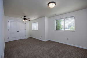 Unfurnished bedroom featuring dark carpet, multiple windows, baseboards, and a closet
