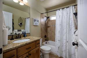 Bathroom featuring vanity, shower / tub combo, toilet, and tile patterned floors