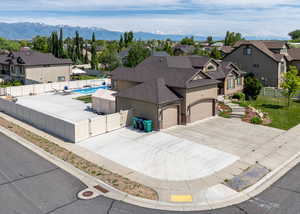 View of front facade featuring a gate, a shingled roof, a residential view, stucco siding, and concrete driveway