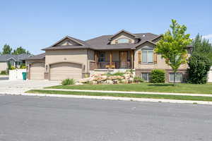View of front of house with stucco siding, a front yard, a garage, driveway, and a porch