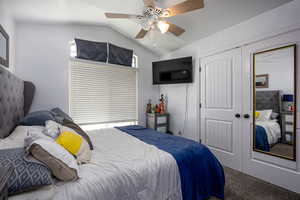 Bedroom featuring lofted ceiling, carpet floors, a closet, and a ceiling fan