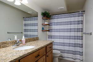 Bathroom featuring vanity, toilet, curtained shower, and tile patterned flooring