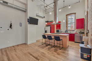 Kitchen with stainless steel appliances, rail lighting, a center island, light countertops, and light wood finished floors