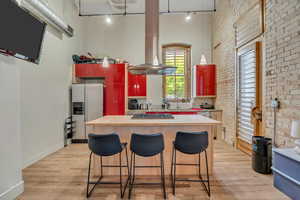 Kitchen featuring appliances with stainless steel finishes, rail lighting, brick wall, light wood-type flooring, and a sink