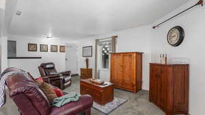 Living area with light colored carpet, many windows and a textured ceiling