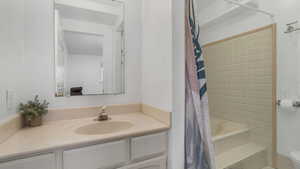 Downstairs Primary Bedroom ensuite bathroom with vanity, a shower with curtain, and toilet
