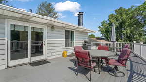 Wooden deck featuring outdoor dining area and a grill