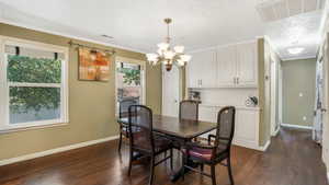 Dining area featuring a chandelier, baseboards, dark wood-style flooring, and crown molding