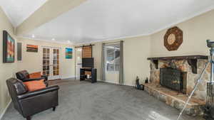 Carpeted living room with french doors, a fireplace, baseboards, ornamental molding, and recessed lighting