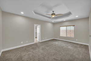 Empty room featuring carpet, baseboards, recessed lighting, a raised ceiling, and a ceiling fan