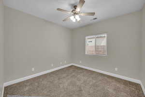 Carpeted empty room featuring baseboards and ceiling fan