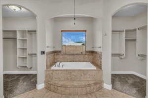 Full bathroom with a bath, a walk in closet, and baseboards