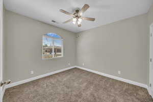 Spare room with a ceiling fan, carpet, and baseboards