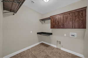 Laundry area with baseboards, cabinet space, washer hookup, hookup for a gas dryer, and light tile patterned floors