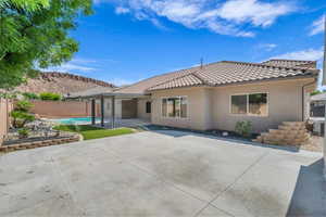 Back of house with a tile roof, stucco siding, a fenced backyard, and a patio area
