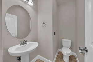Half bathroom featuring toilet, baseboards, and a sink