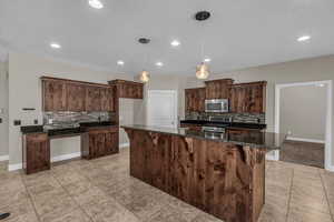 Kitchen with appliances with stainless steel finishes, tasteful backsplash, light tile patterned floors, baseboards, and recessed lighting