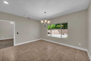 Tiled spare room with a chandelier, baseboards, recessed lighting, and a textured ceiling