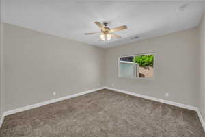 Spare room featuring carpet flooring, ceiling fan, and baseboards