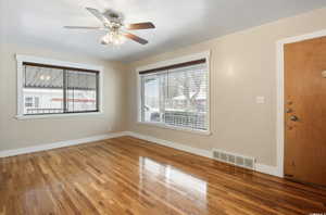 Unfurnished room with wood finished floors, a ceiling fan, and baseboards